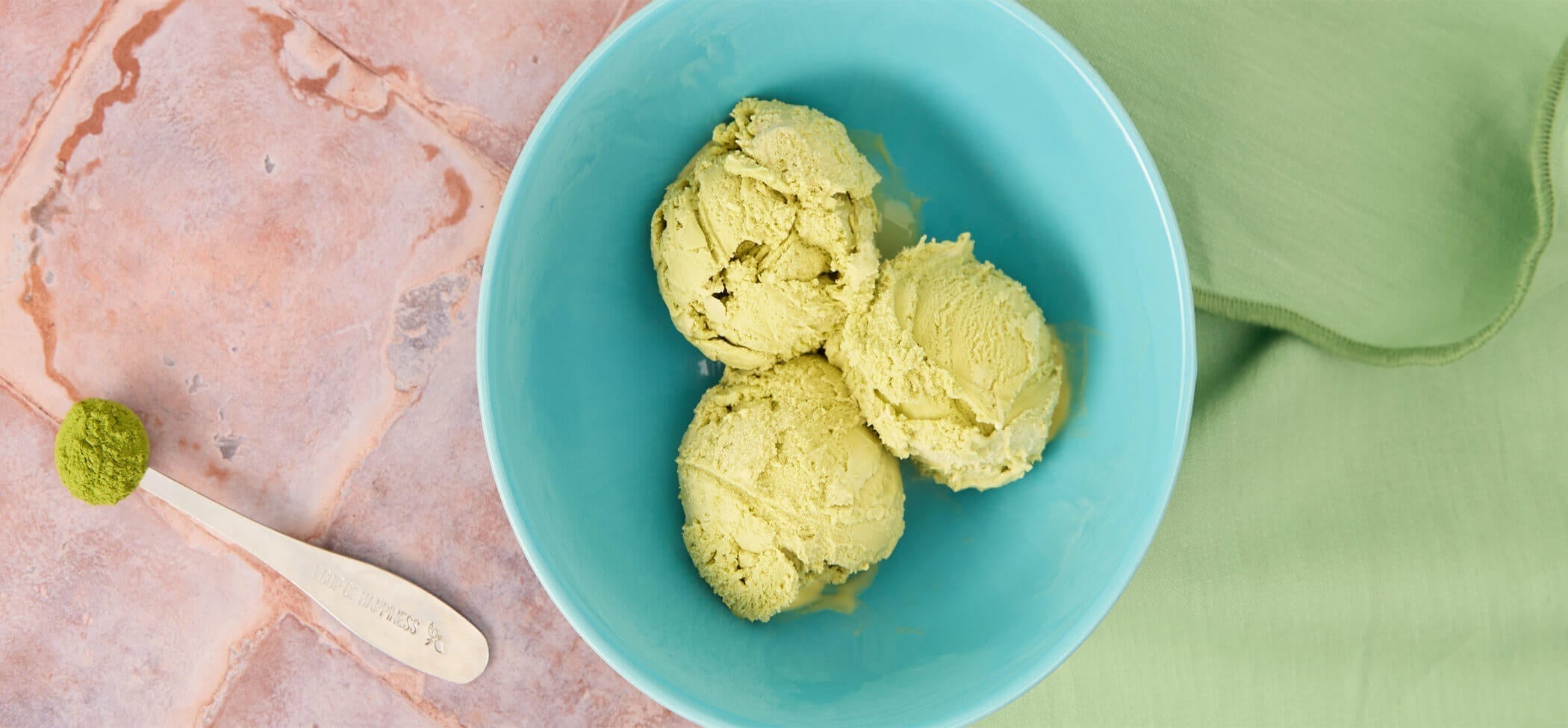 Matcha tea ice cream in a blue bowl and spoon with matcha tea powder