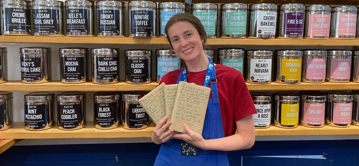 tea mixologist holding three books wrapped in wrapping paper