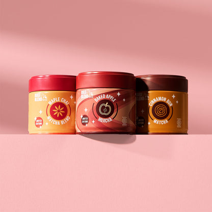 cinnamon bun matcha tin &amp; baked apple hojicha tin &amp; maple chai matcha blend tin on a pink table