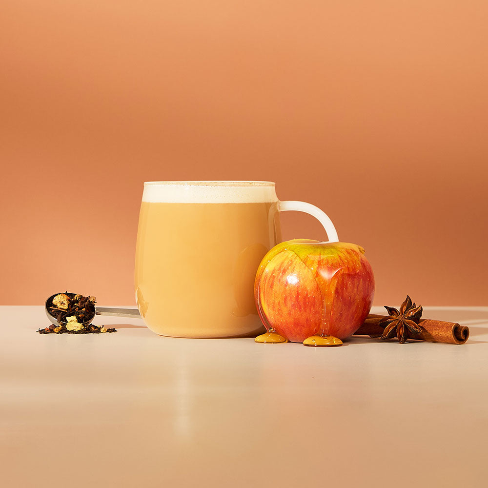 hot maple apple chai latte &amp; ingredients including chai spices &amp; apple covered in maple syrup and perfect tea spoon filled with loose leaf tea