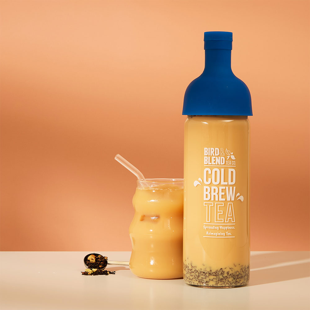 iced maple apple chai latte &amp; perfect tea spoon filled with loose leaf tea with a sapphire blue cold brew tea bottle filled with tea with milk